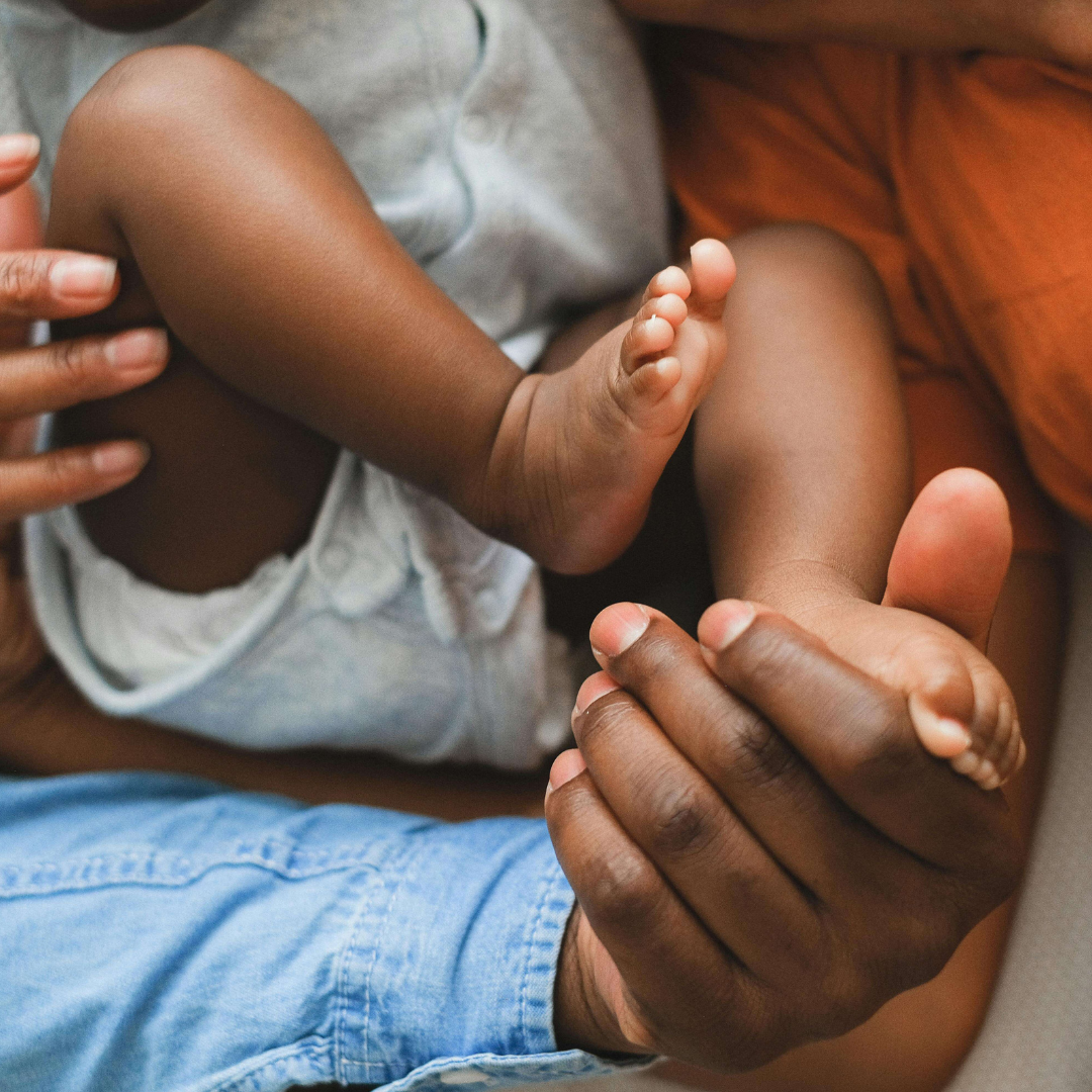 Baby feet resting in caregiver’s hands showing skin-to-skin contact during postpartum recovery