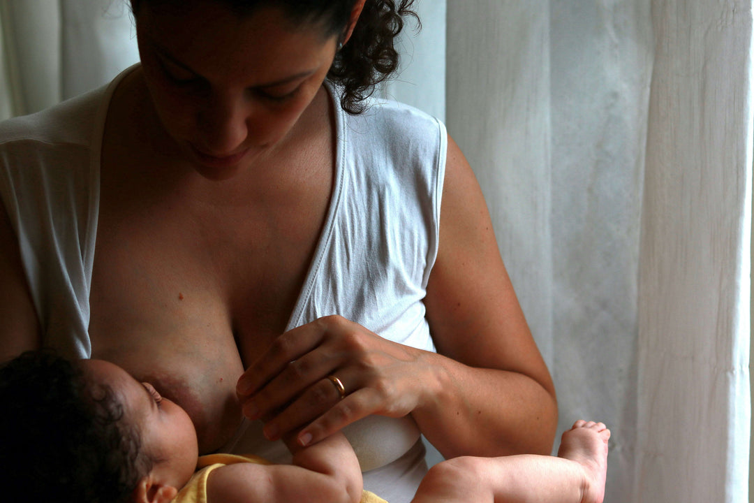 mother breastfeeding newborn during early postpartum period