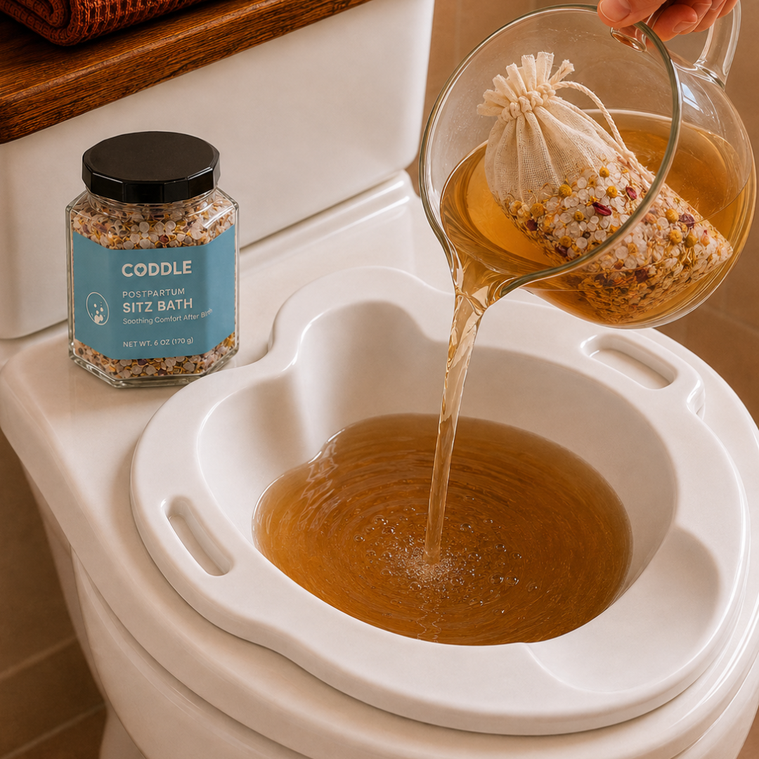CODDLE Postpartum Sitz Bath botanical infusion being poured from a glass pitcher into a sitz bath basin.