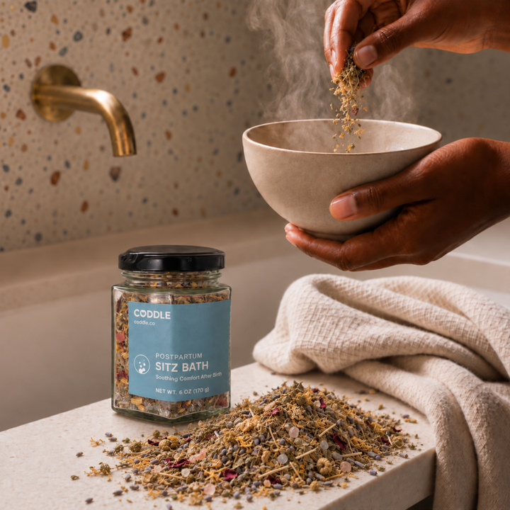 Person preparing a soothing postpartum sitz bath with CODDLE Sitz Bath botanicals in a warm, spa-inspired bathroom.