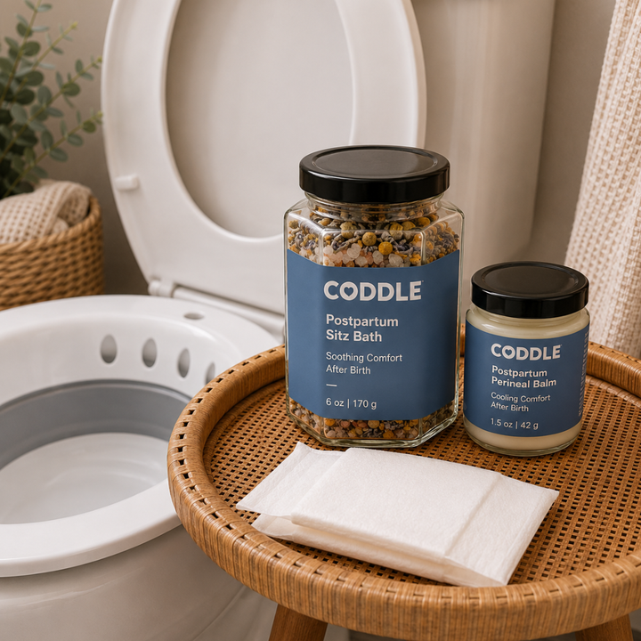 CODDLE Perineal Care After Birth Kit featuring Postpartum Sitz Bath, Postpartum Perineal Balm, postpartum wipes, and a sitz bath basin arranged in a bright bathroom for soothing postpartum recovery after birth.