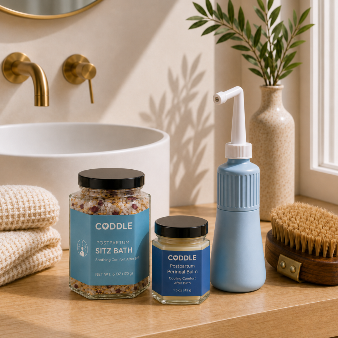 CODDLE Perineal Recovery Kit displayed in a spa-inspired bathroom with Postpartum Sitz Bath, Postpartum Perineal Balm, and a peri bottle to support soothing postpartum recovery.
