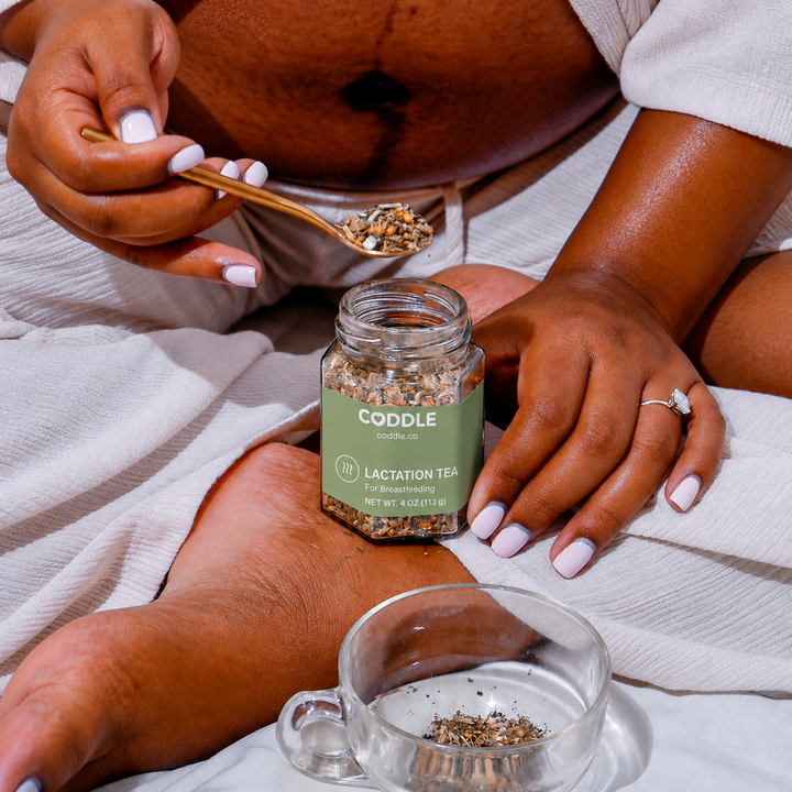 Pregnant mother scooping CODDLE Lactation Tea into a clear glass cup during her tea preparation ritual.