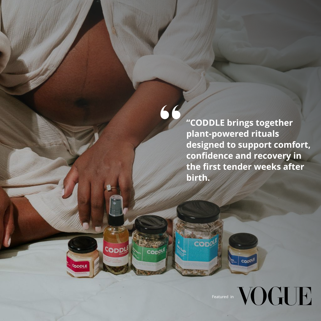 Real postpartum mother sitting with CODDLE postpartum recovery kit and plant-powered maternal wellness products during the fourth trimester.