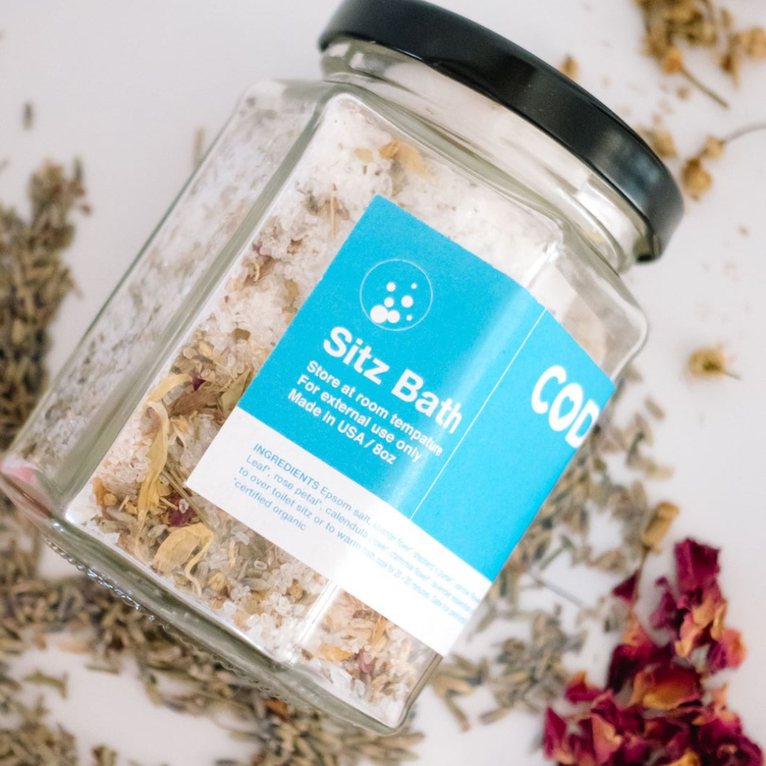 Close up of CODDLE herbal sitz bath soak with dried botanical ingredients for postpartum recovery.