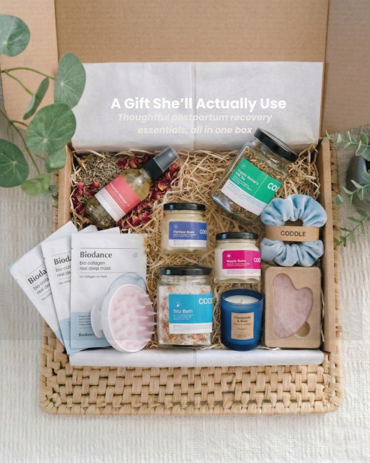 Postpartum recovery gift box with sitz bath, balms, and self-care essentials arranged in a basket.